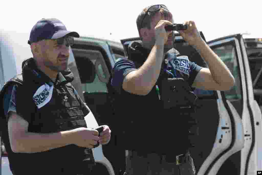Members of the OSCE mission to Ukraine examine the area of the Malaysia Airlines plane crash near the village of Hrabove, Donetsk region, eastern Ukraine, Aug. 1, 2014. 