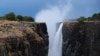 FILE - Visitors walk along a walkway as spray rises up from a flowing section of Victoria Falls, Zimbabwe, Dec. 4, 2019. 