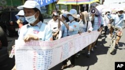 In this photo taken on Friday, May 4, 2012, Cambodian protesters from Boueng Kak lake march with a banner displaying the thumb prints of fellow land owners who have been evicted from their homes, as they demand compensation, in Phnom Penh, file photo.