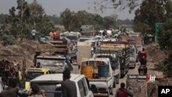 FILE - This photo provided by Nabaa Media, a Syrian opposition media outlet, shows people in their vehicles fleeing from Daraa, southern Syria, June 28, 2018. 