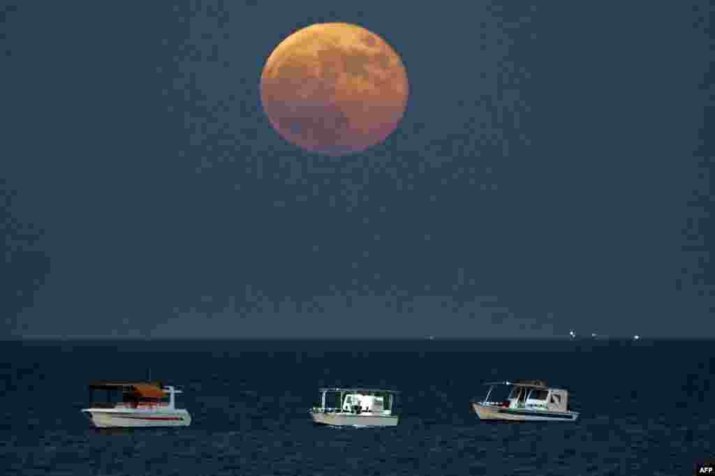 Los barcos pesqueros navegan mientras la superluna llena "de la cosecha" se eleva sobre las aguas del Golfo frente a la costa de la ciudad de Kuwait el 18 de septiembre 2024. 