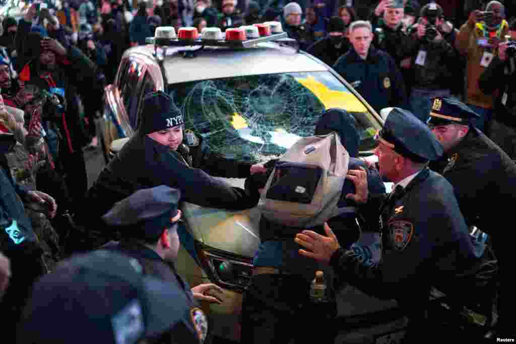 Los policías sujetan a un manifestante en un vehículo policial, el día de la publicación de un video que muestra a policías golpeando a Tyre Nichols, quien murió tres días después.