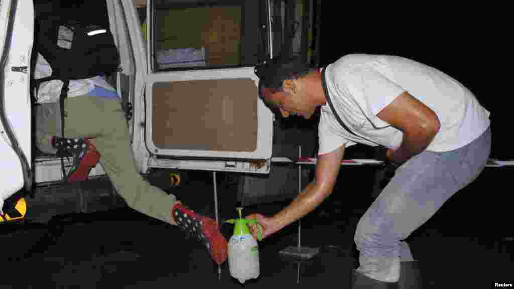 Un travailleur de l'ONG international Médecins Sans Frontières pulvérise les bottes de son collègue avec un désinfectant au chlore pour prévenir Ebola à Monrovia, Liberia, le 20 ocotbre 2014. REUTERS/James Giahyue