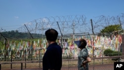 Visitors walk near the barbed wire fences decorated with ribbons written with messages wishing for the reunification of the two Koreas at the Imjingak Pavilion in Paju, South Korea, Sept. 24, 2021.