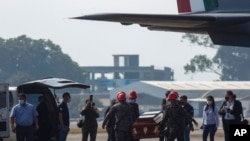 Un ataúd que contiene los restos de un migrante guatemalteco muerto en un accidente de camión en el sur de México, es transportado a un vehículo que esperaba en la pista del Aeropuerto Internacional La Aurora en la Ciudad de Guatemala, el 30 de diciembre de 2021. 