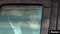 FILE - U.S. President Donald Trump waves to supporters as he briefly rides by in the presidential motorcade in front of Walter Reed National Military Medical Center, Oct. 4, 2020.