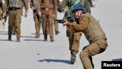 FILE - An Indian police officer aims his pellet gun towards demonstrators during a protest after Friday prayers in Srinagar, March 5, 2021. 