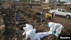 FILE - Health workers bury the body of a suspected Ebola victim at a cemetery in Sierra Leone, Dec. 21, 2014.
