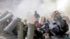Manifestantes se ponen a cubierto mientras chocan con agentes de la policía antidisturbios durante una protesta contra el golpe militar en Rangún, Myanmar, el 28 de febrero de 2021.