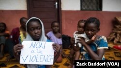 A young displaced Muslim girl holds a sign saying “No to Violence” at a displaced persons site, the Catholic church in Bangassou, Central African Republic.