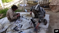 FILE - In this file photo released on June 16, 2015, by Islamic State militant group supporters on an anonymous photo sharing website, Islamic State militants clean their weapons in Deir el-Zour city, Syria.
