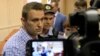 Russian opposition leader Alexei Navalny (L, front) is escorted by an Interior Ministry officer inside a courtroom in Kirov, July 18, 2013. 