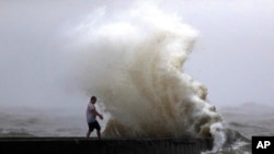 Gelombang ombak yang dipicu oleh Badai Tropis Cristobal saat bergerak mendekati Pantai Louisiana, menghempas pantai di dermaga dekat Orleans Harbor, Lake Pontchartrain, New Orleans, Minggu, 7 Juni 2020, mengenai seorang pria yang berdiri di sana. (Foto AP / Gerald Herbert)