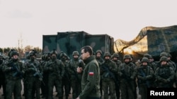 Poland's Prime Minister Mateusz Morawiecki addresses service members near the frontier, as hundreds of migrants gather on the Belarusian side of the border with Poland in an attempt to cross it, near Kuznica Bialostocka, Poland, Nov. 9, 2021. 
