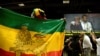 FILE - A member of the Ethiopian diaspora holds a national flag as Ethiopia's Prime Minister Abiy Ahmed (in white, on monitor) is hugged after calling on them to return, invest and support their native land, in Washington, July 28, 2018.