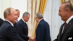 Russian President Vladimir Putin, left, shakes hands with Turkish Foreign Minister Mevlut Cavusoglu during their meeting in the Kremlin in Moscow, Russia, Aug. 24, 2018. 