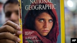 Pakistan's Inam Khan, owner of a book shop shows a copy of a magazine with the photograph of Afghan refugee woman Sharbat Gulla, from his rare collection in Islamabad, Pakistan, Oct. 26, 2016. 