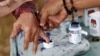 Seorang petugas pemilu membantu seorang perempuan lanjut usia untuk menandai jarinya dengan tinta setelah memberikan suaranya pada Pilkada di Tangerang, Banten, 27 Juni 2018. (Foto: REUTERS/Willy Kurniawan)