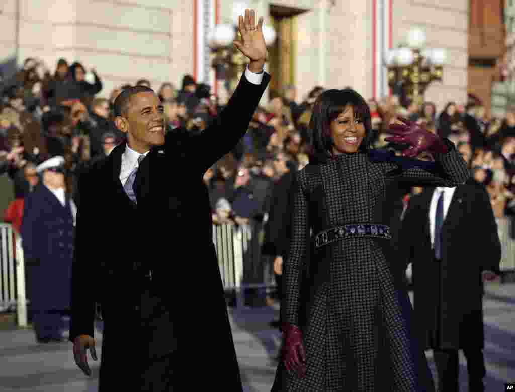 President Barack Obama and first lady Michelle Obama waves as they walk down Pennsylvania Avenue near the White House during the Inauguration parade, Jan. 21, 2013.