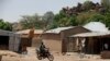 FILE - An unidentified man rides a motorbike past houses in Chibok, Nigeria, May 19, 2014. 