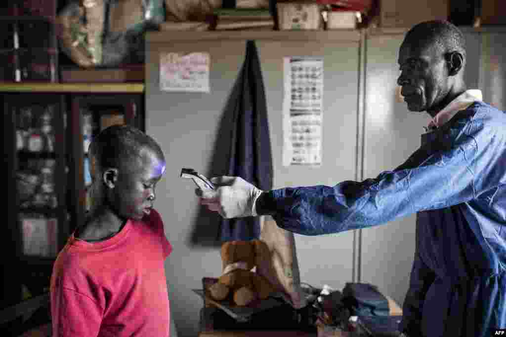 Un jeune enfant de la rue, également appelé Talibe, prend sa température dans en zone de quarantaine, dans un refuge pour enfants de rue nouvellement arrivés à l'extérieur de Dakar, le 10 avril 2020.