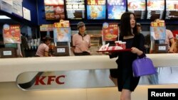 A woman holds food inside a KFC restaurant in Beijing, May 9, 2013. Yum Brands Inc, the largest foreign fast-food chain in China, is strengthening its media strategy in the country in a bid to win back customer loyalty after a series of food scares that 