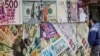 A man takes a photograph of exchange rates in front of an exchange point that is displaying images of different currencies, in Cairo, March 6, 2024. Egypt announced that the International Monetary Fund will increase its bailout loan to $8 billion.
