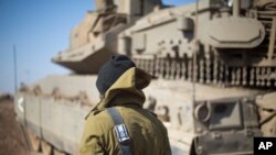 FILE - An Israeli soldier stand by a tank near the border with Syria in the Israeli-controlled Golan Heights, Monday, Nov. 28, 2016. 