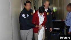 FILE - Special agents with U.S. Immigration and Customs Enforcement's Homeland Security Investigations escort Jorge Sosa, a former Guatemalan army commando, following his extradition from Canada, Los Angeles International Airport, Sept. 2012.