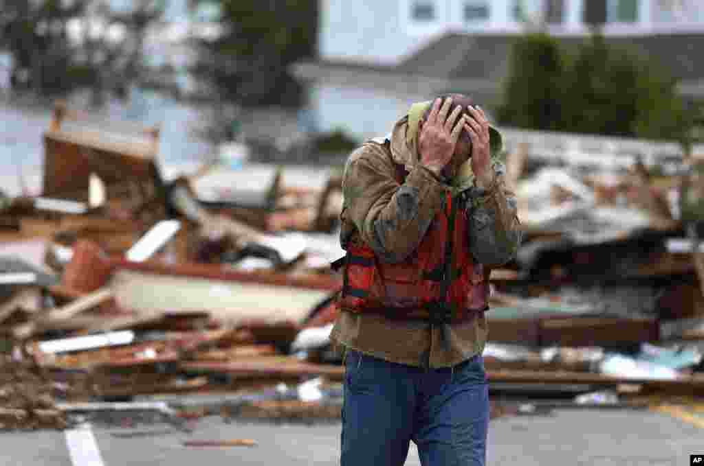 Brian Hajeski, 41, dari Brick, New Jersey, menutup wajahnya setelah melihat reruntuhan rumahnya yang disapu sampai Jembatan Mantoloking Bridge pada pagi hari setelah badai super Sandy melanda Mantoloking, New Jersey (30/10). 