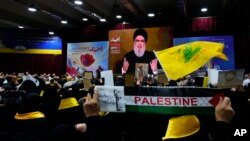 Los partidarios de Hizbulá levantan sus puños a modo de saludo mientras escuchan un discurso del líder, Sayyed Hassan Nasrallah, a través de un enlace de video, en una ceremonia que marca el "Día del Mártir de Hezbollah", en el sur de Beirut, Líbano. Sábado, 11 de noviembre.