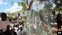 Ma'aikatan kungiyar agajin Oxfam su na nuna wa mutanen wani kauye yadda ake amfani da gidan sauro a kasar Zimbabwe