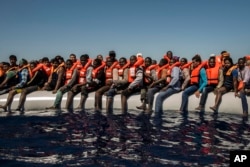Refugees and migrants from Eritrea, Mali, Bangladesh and other countries wait on board a dinghy to be rescued in the Mediterranean Sea, 27 kilometers (17 miles) north of Sabratha, Libya, July 19, 2016.