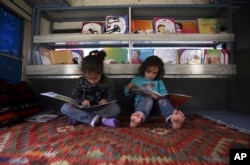 FILE - Afghan children read books inside a library on wheels, in Kabul, Afghanistan, March 10, 2018.