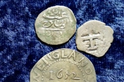 A 17th century Arabian silver coin, top, that research shows was made in 1693 in Yemen, rests near an Oak Tree Shilling made in 1652 by the Massachusetts Bay Colony, below, and a Spanish half real coin from 1727. (AP Photo/Steven Senne)