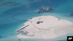 In this Feb. 25, 2014 file photo taken by surveillance planes and released May 15 by the Philippine Department of Foreign Affairs, a Chinese vessel, top center, is used to expand structures and land on the Johnson Reef.