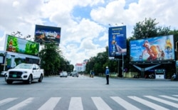 Traffic police oversees a regular traffic at the Chamkarmon intersection where billboards advertising alcohol stand in Phnom Penh, on Oct. 29, 2021. (Kann Vicheika/VOA Khmer)
