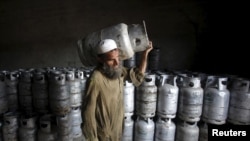 FILE - A worker carries a cylinder of Liquified Petroleum Gas at a gas distribution center in Peshawar, Pakistan April 29, 2015.