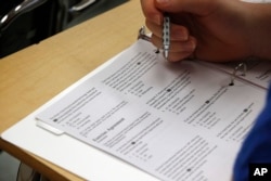 In this photo taken Jan. 17, 2016, an educator reviews a college test.
