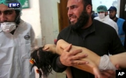 A photo provided by the Syrian anti-government activist group Edlib Media Center shows a man carrying a child following a suspected chemical attack at a makeshift hospital in the town of Khan Sheikhoun, Idlib province, Syria, April 4, 2017.