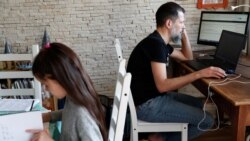 Un padre de familia comparte el espacio de trabajo con su hija en esta imagen captada en Budapest, Hungría.