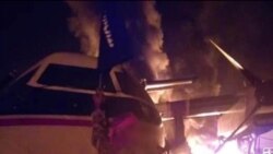 Una imagen distribuida por al Shabaab después del ataque a una base militar en Kenia muestra a un militante de al Shabaab en Somalia, sosteniendo la bandera del grupo junto a un avión en llamas, que se dice que está en el aeródromo de Manda Bay, el 5 de enero de 2020.