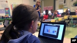 In this Sept. 20, 2018 photo, fifth grade student Ashlynn De Filippis, left, works math problems on the DreamBox system as teacher Heather Dalton, center rear, works with other students in class at Charles Barnum Elementary School in Groton, Conn. (AP Photo)