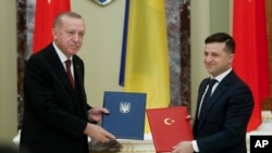 Ukrainian President Volodymyr Zelenskiy, right, and Turkey's President Recep Tayyip Erdogan pose for a photo during a signing ceremony in Kyiv, Ukraine, Feb. 3, 2020.