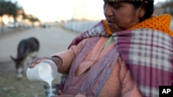 FILE - Donkey milk vendor Andrea Aruquipa, an Aymara indigenous woman, pours a glass of milk from her donkey for a client in El Alto, Bolivia, May 24, 2016.