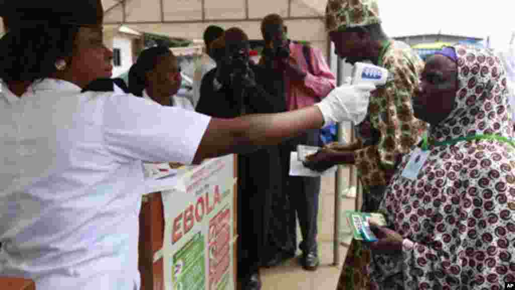 Wani jami’in kula da lafiyar matafiya na amfani da ma’aunin zafin jiki ya na yiwa Maniyyata gwajin cutar Ebola a ranar goma sha takwas ga watan satumba shekarar dubu biyu da goma sha hudu.