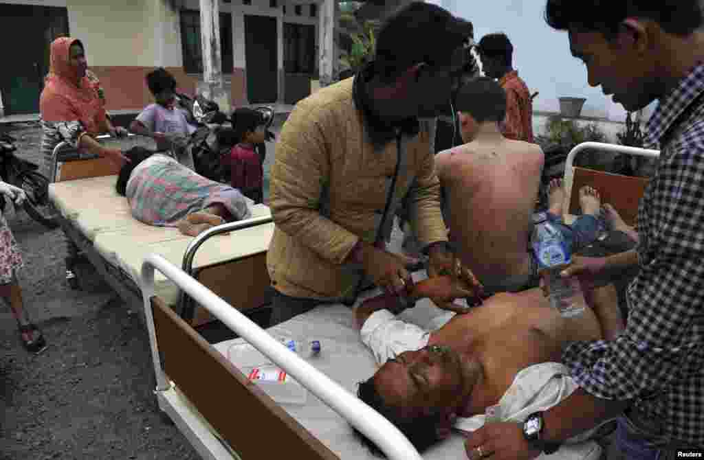 Injured residents receive treatment outside the local clinic after a strong earthquake hit in Bener Meriah district, July 2, 2013.