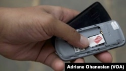 FILE - A mobile phone user checks his SIM card.