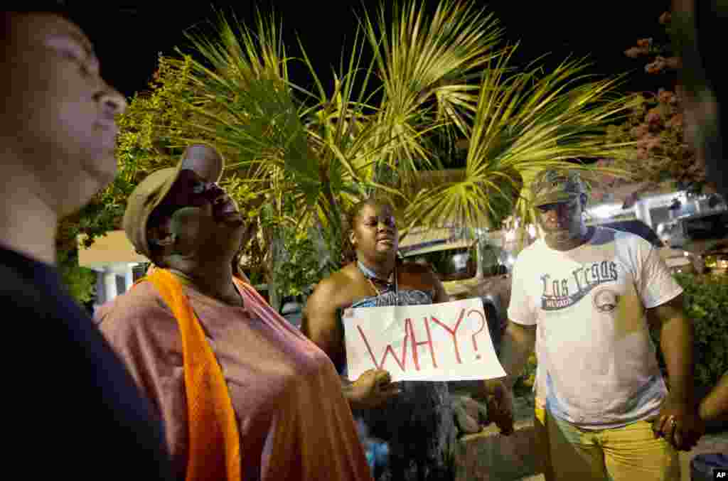 Surreace Cox, of North Charleston, S.C., holds a sign during a prayer vigil down the street from the Emanuel AME Church early Thursday, June 18, 2015, following a shooting Wednesday night in Charleston, S.C.