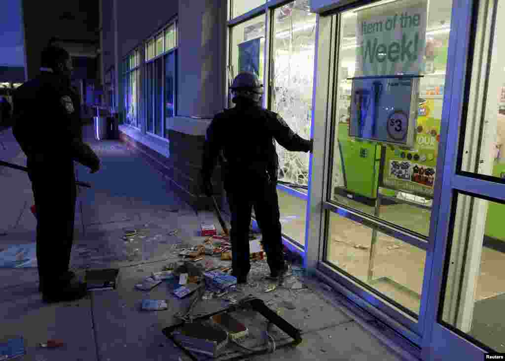 Baltimore police officers arrive at a "Deals" store that was just vandalized and looted by rioters as darkness falls during clashes between rioters and police in Baltimore, Maryland, April 27, 2015.